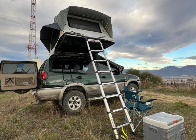 Off-Road 4x4 Camper with an open camping tent. A ladder that gets you to the ground along with a fridge and a chair to relax and enjoy Albania